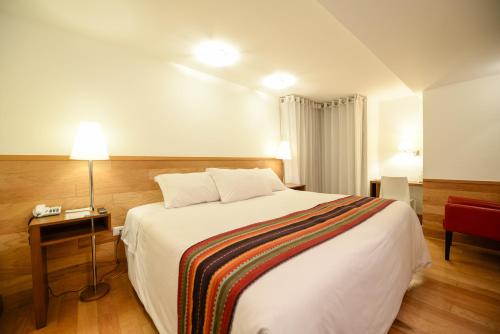 a hotel room with a bed and a table with a lamp at Hotel Plaza de Armas Cusco in Cusco