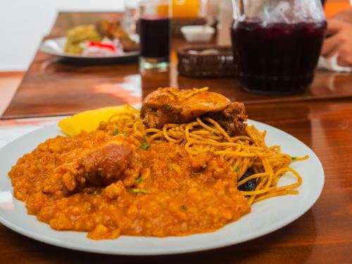 a plate of food with meat and spaghetti on a table at Casa Hotel Mamaluna in Lunahuaná