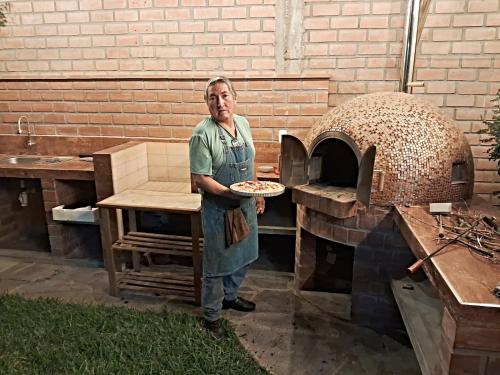 a man standing in front of a pizza oven at Casa Hotel Mamaluna in Lunahuaná