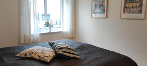 1 dormitorio con 1 cama con 2 almohadas y ventana en Fiskerhuset i Øster Hurup - i byen, ved stranden en Øster Hurup