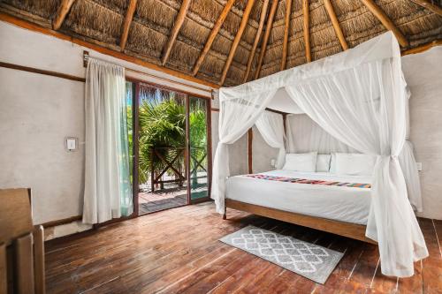 a bedroom with a bed and a large window at Xhule Tulum in Tulum