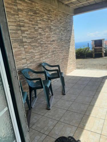 two green chairs sitting on a patio with the ocean at Casa vicente in Santa Cruz das Flores