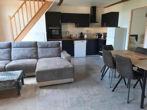 un salon avec un canapé et une table et une cuisine dans l'établissement Chez Line et Pierre: Appartement spacieux, lumineux et équipé, à La Bastide-de-Sérou