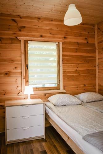 a bedroom with a bed and a window in a cabin at Ranczo Tropical Sun Mielenko in Mielenko