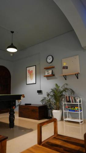 a living room with a piano and a clock on the wall at Sort By Stays, Grand Peddem, Anjuna in Goa