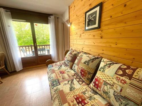salon z kanapą i drewnianą ścianą w obiekcie Appartement cosy au pied des pistes avec piscine, balcon et parking privé - FR-1-505-170 w mieście Flumet