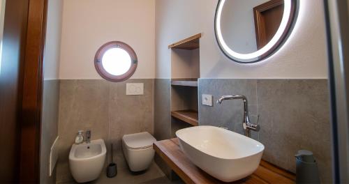a bathroom with a sink and a toilet and a mirror at BOSSEMA 8 Home in Calmasino