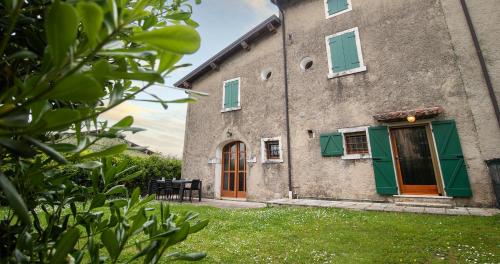 a building with green shutters and a door at BOSSEMA 8 Home in Calmasino