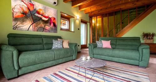 a living room with two green couches and a table at BOSSEMA 8 Home in Calmasino