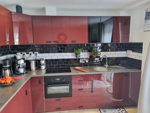 une cuisine avec des armoires rouges et un évier dans l'établissement Les Appart du Sillon, à Pleubian