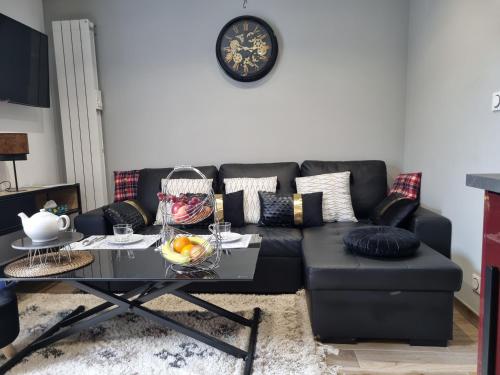 un salon avec un canapé noir et une table dans l'établissement Les Appart du Sillon, à Pleubian