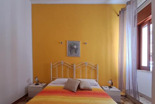 Un dormitorio con una cama y una pared amarilla. en Casa Meraki - Appartamento in centro, en Avola