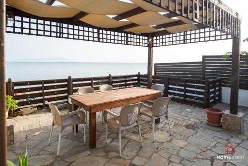 a wooden table and chairs on a patio with the ocean at Sea Side House in Nea Chili