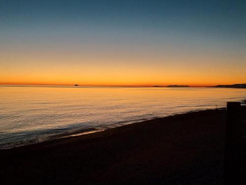 a sunset over the ocean with a beach at Sea Side House in Nea Chili