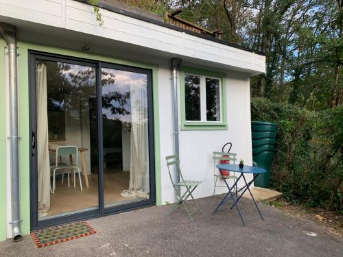 a house with sliding glass doors and a table at Le gîte de la forêt - cocon nature à 5mn du centre in Neauphle-le-Château