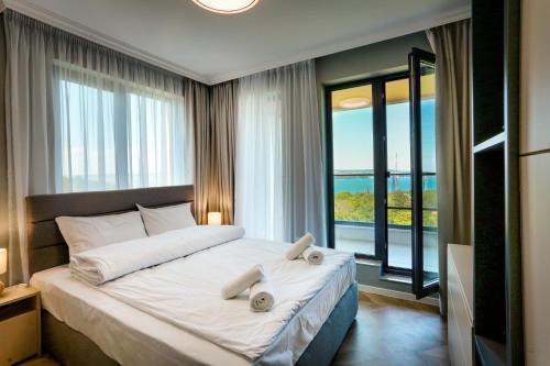 a bedroom with a large bed with a large window at Saint George apartments in Varna City