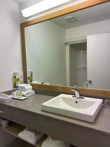 a bathroom with a sink and a large mirror at Hôtel Énergie Shawinigan in Shawinigan
