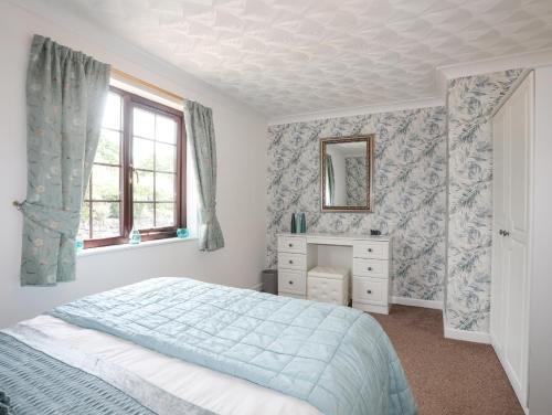 um quarto com uma cama, uma cómoda e um espelho em Cae Ffynnon em Gaerwen