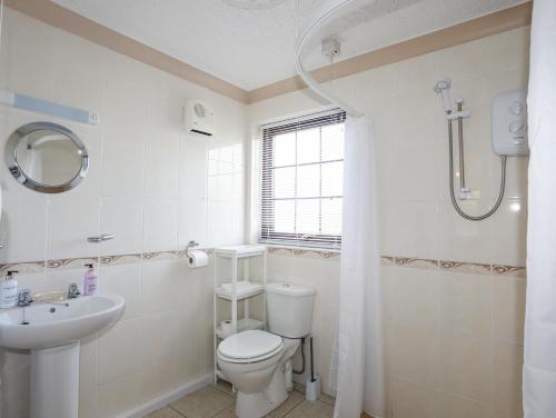 uma casa de banho branca com um WC e um lavatório em Cae Ffynnon em Gaerwen