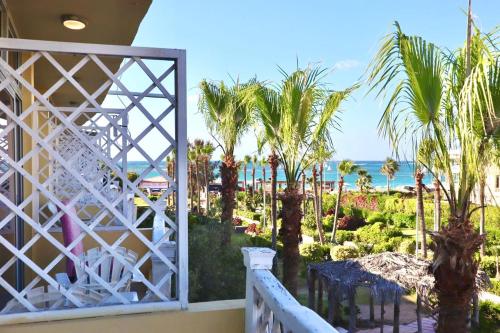 balcón con palmeras y vistas al océano en Paradise Inn Beach Resort en Alexandría