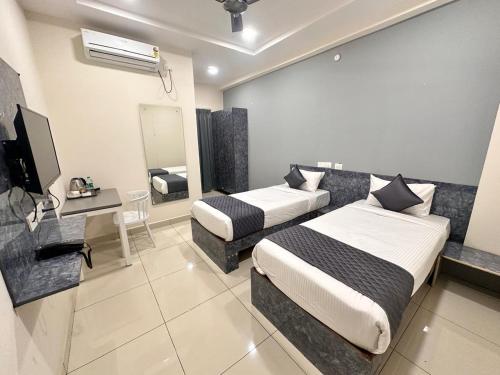 a hotel room with two beds and a television at Hotel Aerotel,Hyderabad in Shamshabad