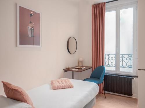 a room with a bed and a chair and a window at Hôtel Biskui in Levallois-Perret