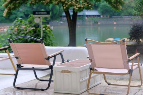 two chairs and a trash can in front of a lake at Ruoli Yangshuo in Yangshuo