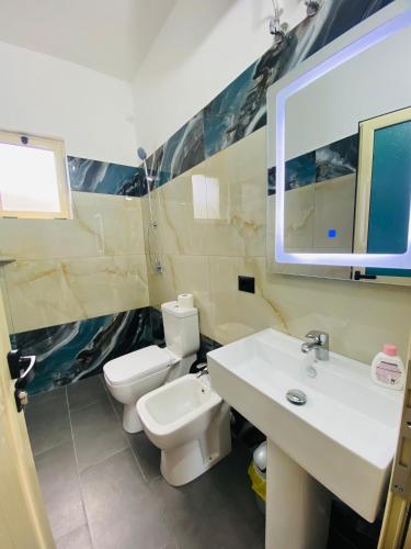 a bathroom with a sink and a toilet and a mirror at "Seaside Pines" Apartments in Vlorë
