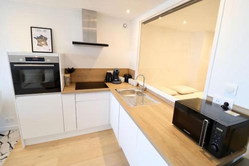 une cuisine avec un évier et un micro-ondes dans l'établissement Le 912 appartement face mer avec balcon, à Le Touquet-Paris-Plage