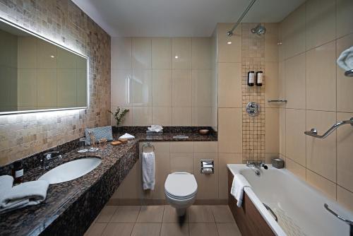 uma casa de banho com um lavatório, um WC e uma banheira em Carlton Hotel Dublin Airport em Cloghran