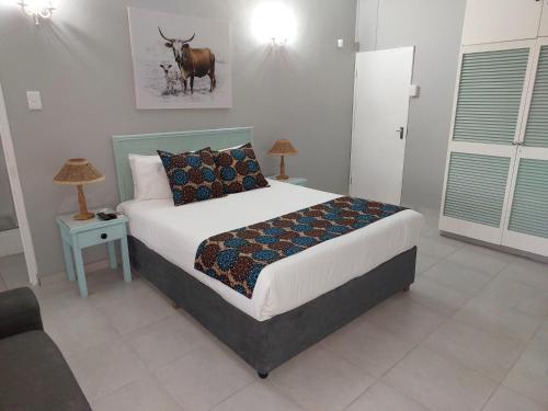 a bedroom with a bed with a cow on the wall at Fairway Guest Lodge in Margate