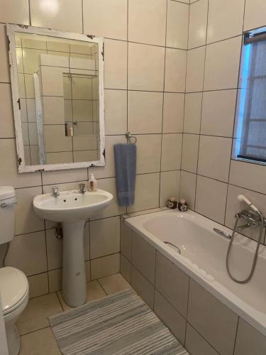 a bathroom with a sink and a tub and a toilet at Pringle Cottage in Benoni