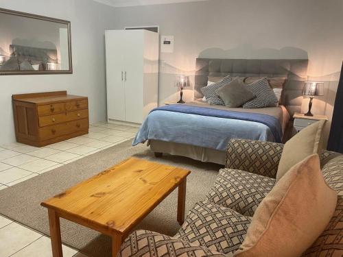 a bedroom with a bed and a couch and a table at Pringle Cottage in Benoni