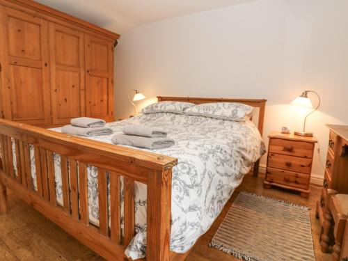 カークビー・ステファンにあるCorner Cottageのベッドルーム1室(木製ベッド1台、タオル付)