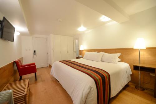 a bedroom with a large white bed and a red chair at Hotel Plaza de Armas Cusco in Cusco