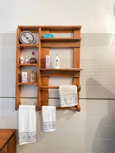 un bagno con tre asciugamani e un orologio su uno scaffale di Nidadi Trulli d'Itria a Martina Franca