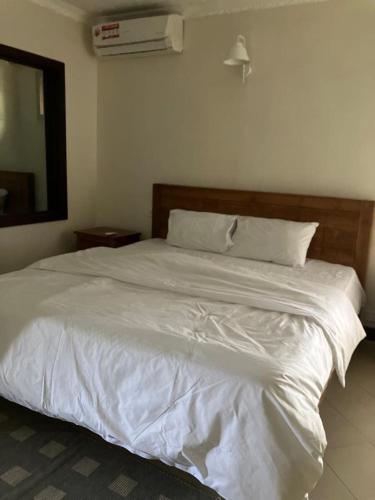 a bedroom with a white bed and a mirror at Sunset Boulevard, Grand Baie in Grand Baie
