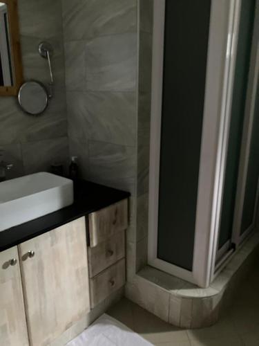 a bathroom with a sink and a shower with a mirror at Sunset Boulevard, Grand Baie in Grand Baie