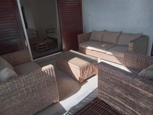 a living room with wicker chairs and a couch at Sunset Boulevard, Grand Baie in Grand Baie