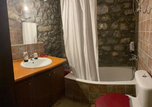 a bathroom with a sink and a tub and a toilet at Potis Stone House in Ákia