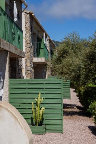a green fence in front of a house with a cactus at Residence Roc E Mare Cargèse in Cargèse