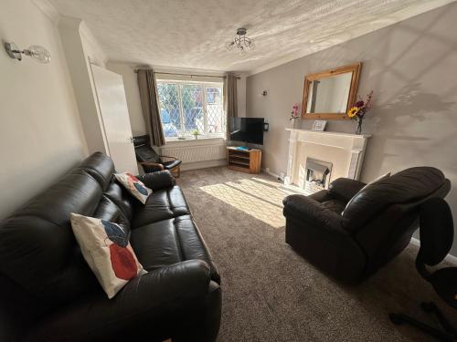 uma sala de estar com um sofá de couro e uma lareira em Hinckley Home Sleeps 5 Complete House em Leicester