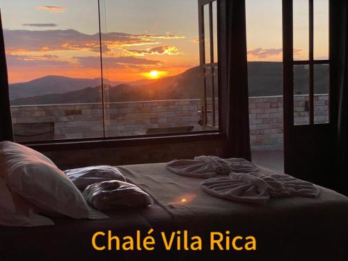a bed in a room with a view of the sunset at Chalé Mirante do Sol in Ouro Preto
