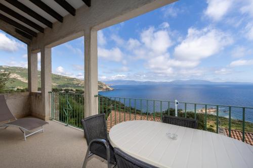 a balcony with a table and chairs and the ocean at Residence Roc E Mare Cargèse in Cargèse