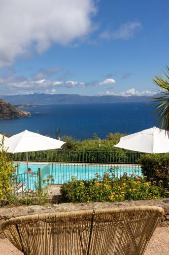 a view of a pool with umbrellas and the ocean at Residence Roc E Mare Cargèse in Cargèse