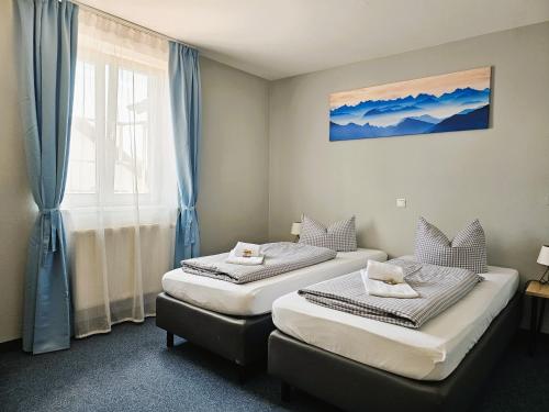 two beds in a room with a window at Novitel Pension Pliening - München Messe in Pliening