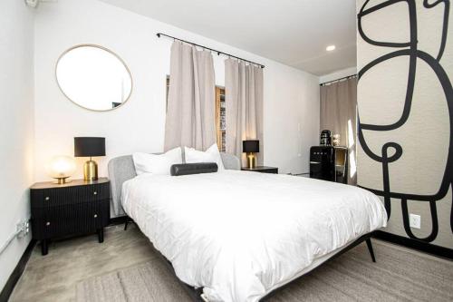 a bedroom with a large white bed with two tables and two mirrors at Steps to Bathhouses, Restaurants, Heart of Downtown, Room # 301 in Hot Springs