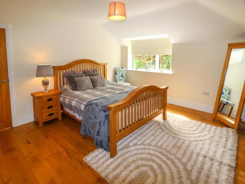 a bedroom with a wooden bed and a window at Bryn Golau in Llangollen