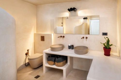 a bathroom with a sink and a toilet and a mirror at Aerie 2bedroom by Thireon in Oia