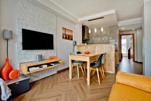 a kitchen and living room with a table and a tv at Rodzinny Apartament we Władku in Władysławowo